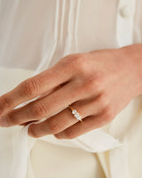 Woman wearing a yellow gold engagement ring with three oval white laboratory grown diamonds.