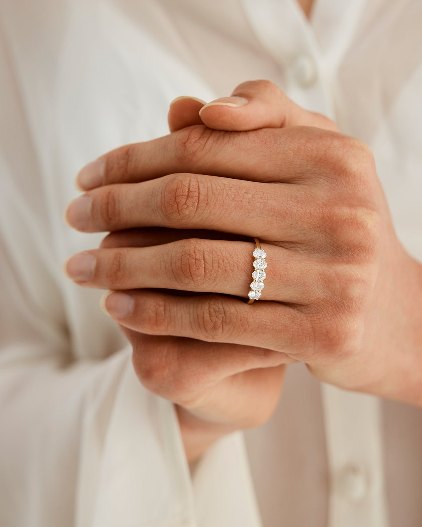 Woman wearing a wrap engagement ring with 5 oval diamonds