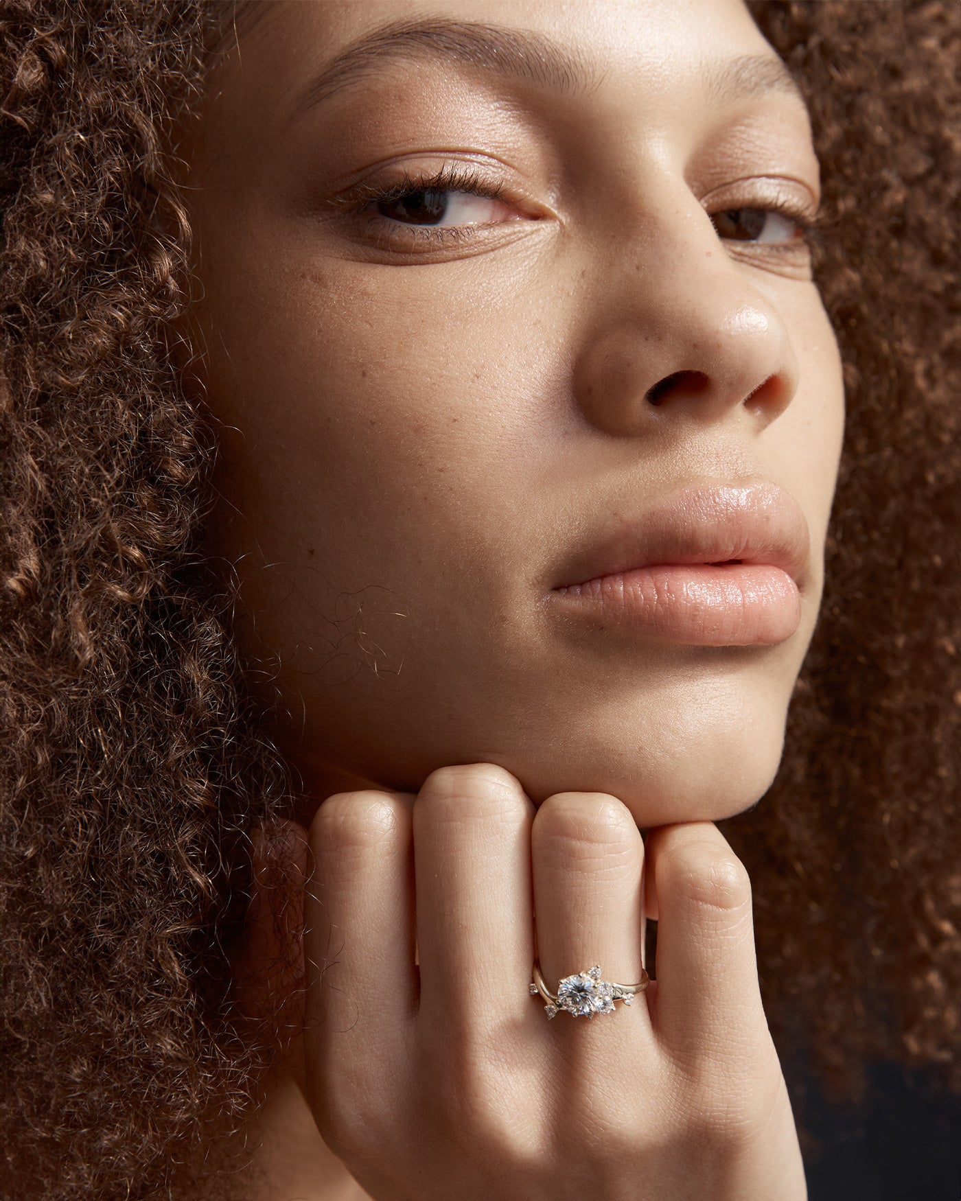 woman wearing a yellow gold  engagement ring with a cluster of laboratory grow diamonds