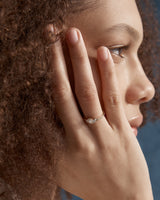 image of a woman wearing  a yellow gold  engagement ring with a cluster of 7 white diamonds