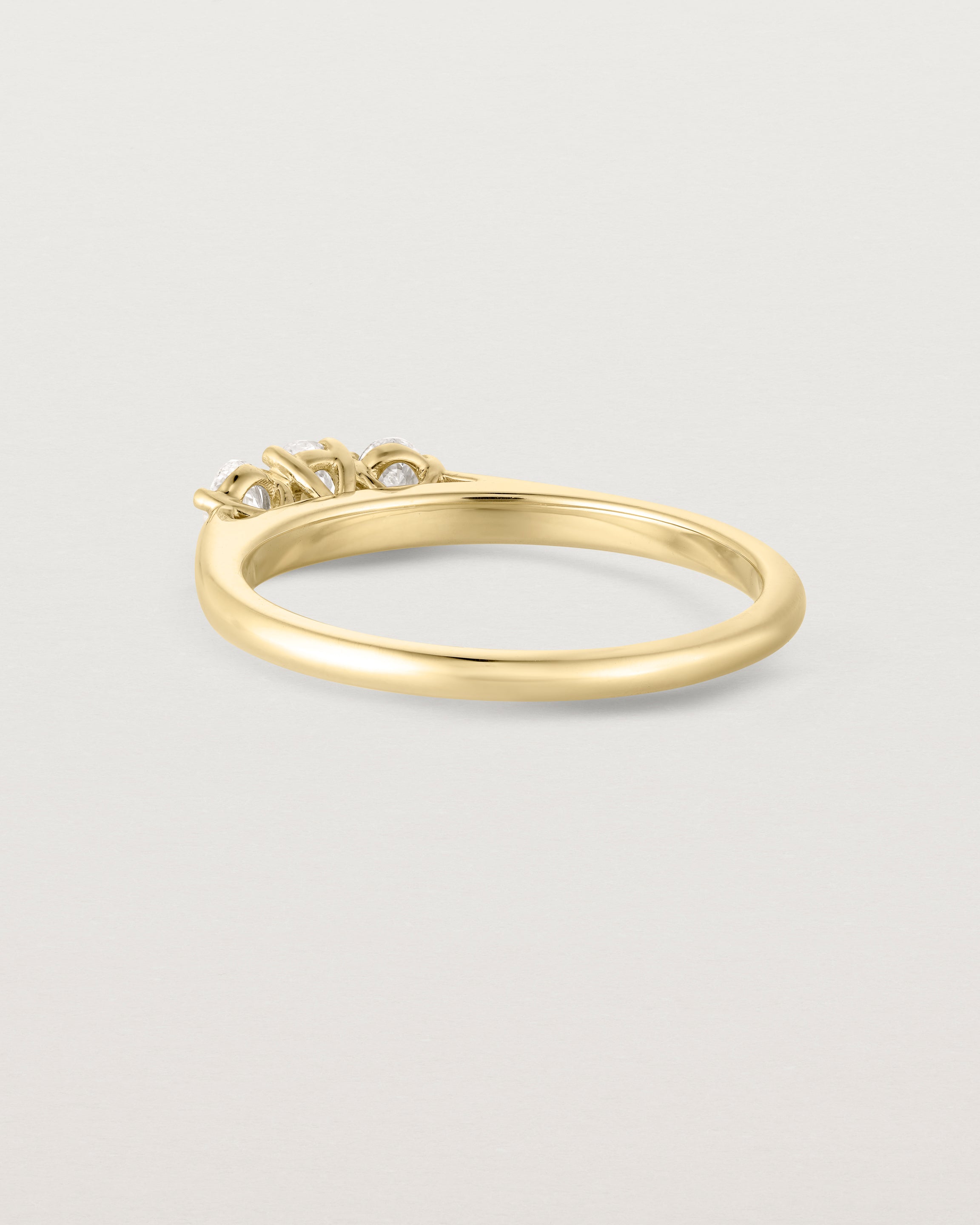 back facing deep etched image of a yellow gold engagement ring with three oval laboratory grown diamonds.