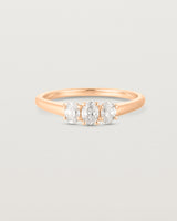 Front on deep etched image of a rose gold engagement ring with three oval white diamonds.