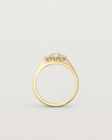 Standing  deep etched image of a yellow gold engagement ring with three oval diamonds.