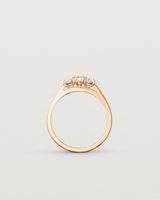 Standing deep etched image of a rose gold engagement ring with three oval white diamonds.