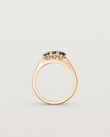 Standing deep etched image of a rose gold engagement ring with three oval sapphire stones.