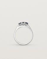 Standing deep etched image of a white gold engagement ring with three oval sapphire stones.