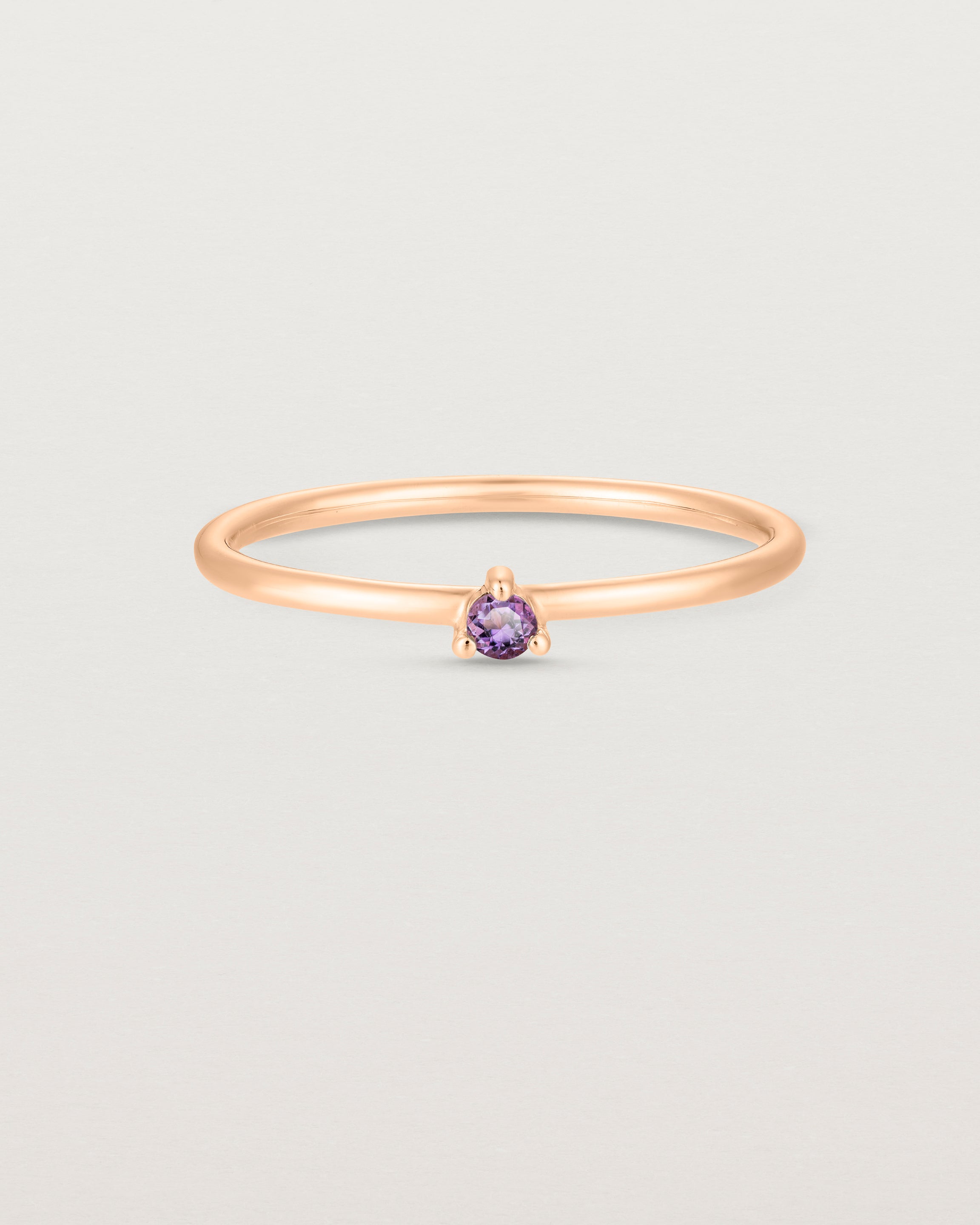 Front facing deep etched image of a rose gold ring with an amethyst birthstone.