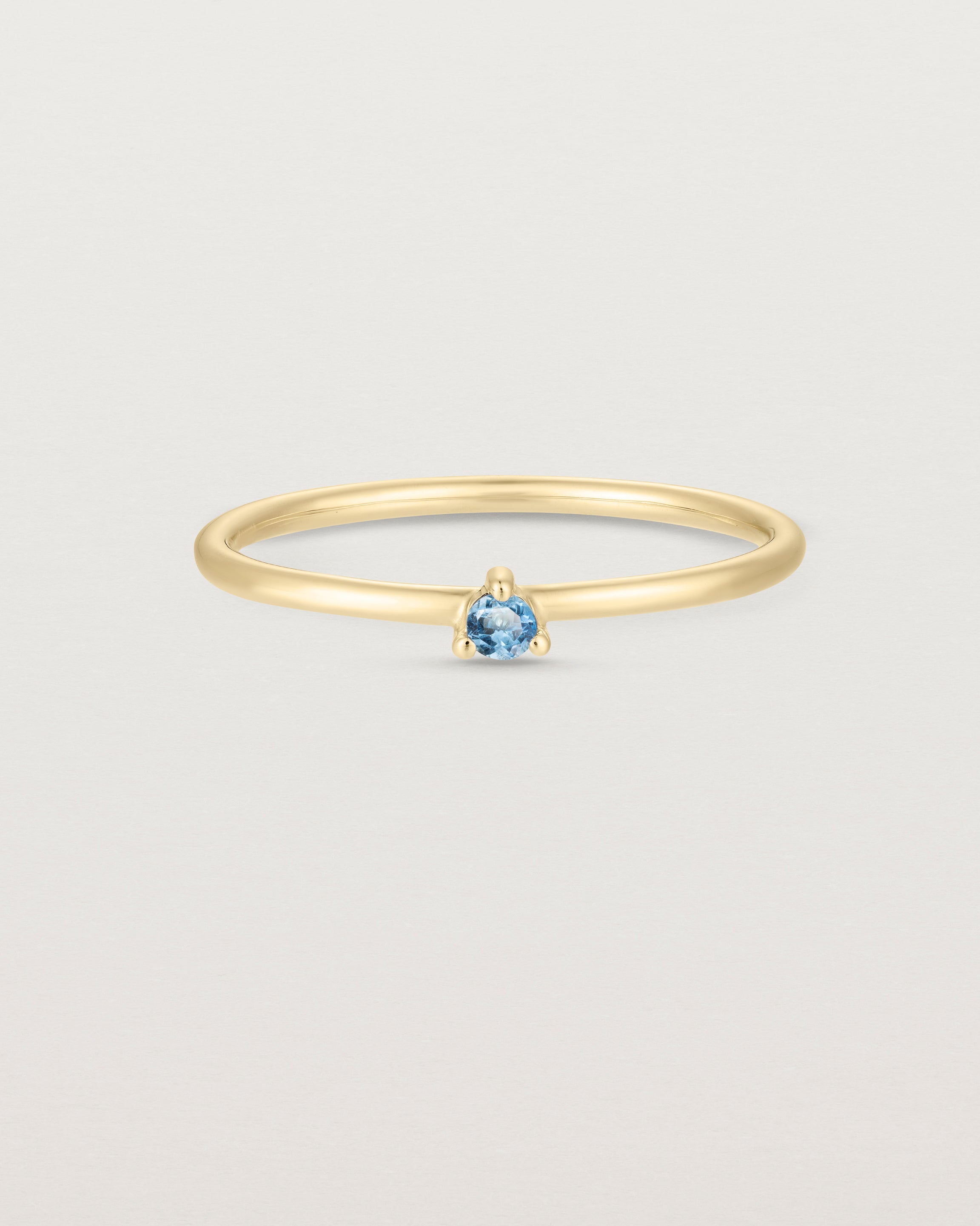 Front facing deep etched image of a yellow gold ring with an aquamarine birthstone.