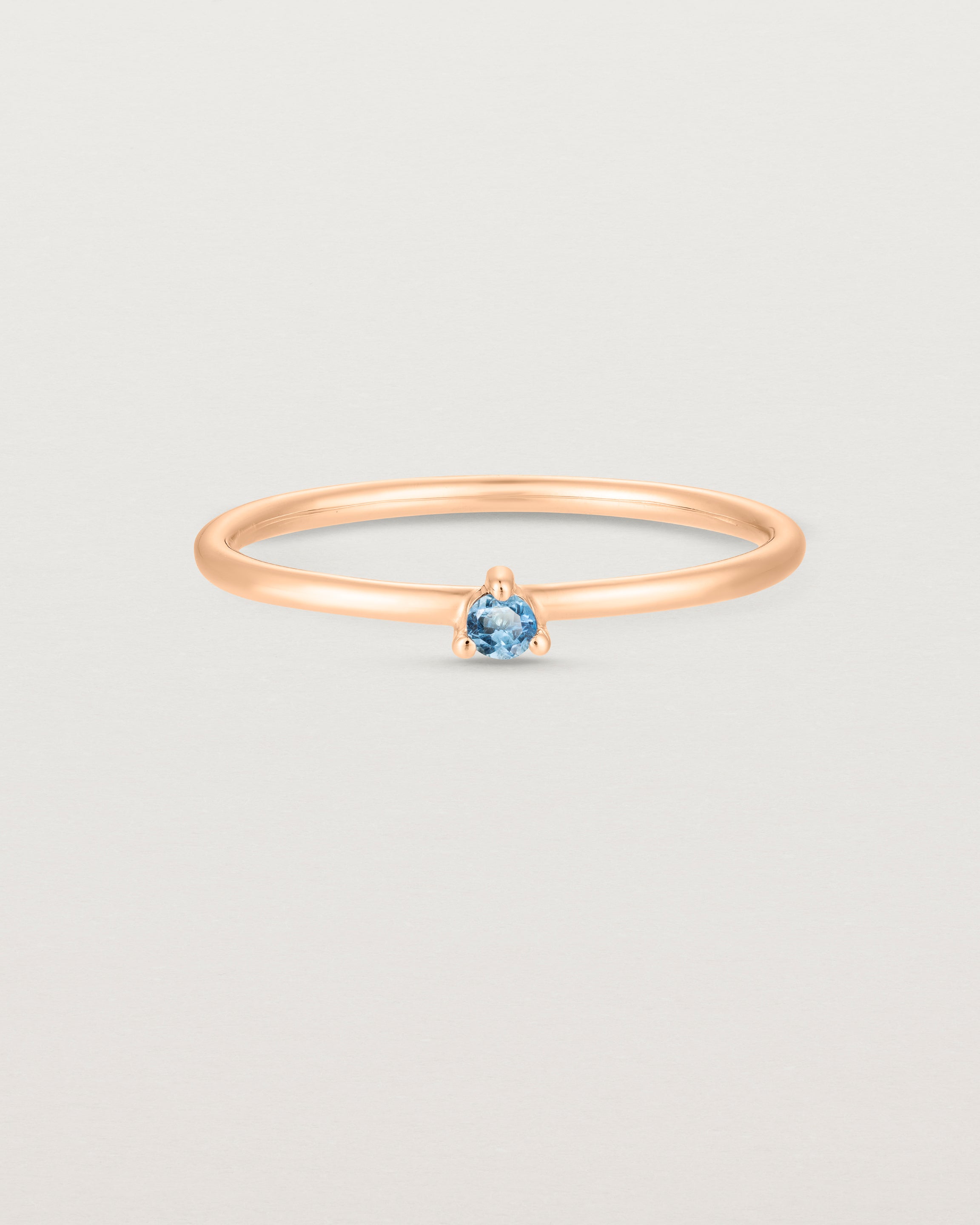 Front facing deep etched image of a rose gold ring with an aquamarine birthstone.