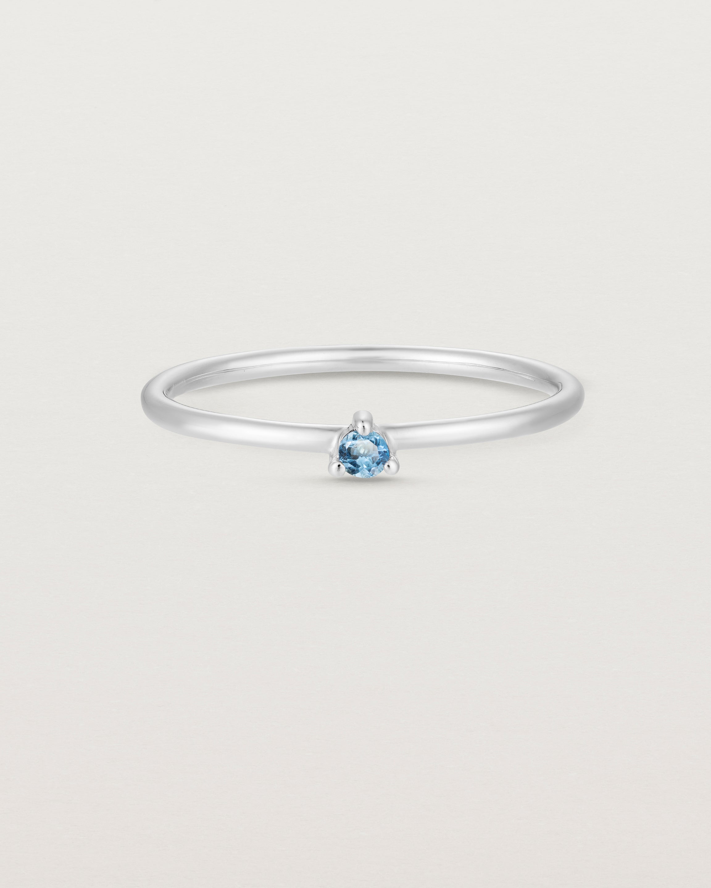 Front facing deep etched image of a white gold ring with an aquamarine birthstone.