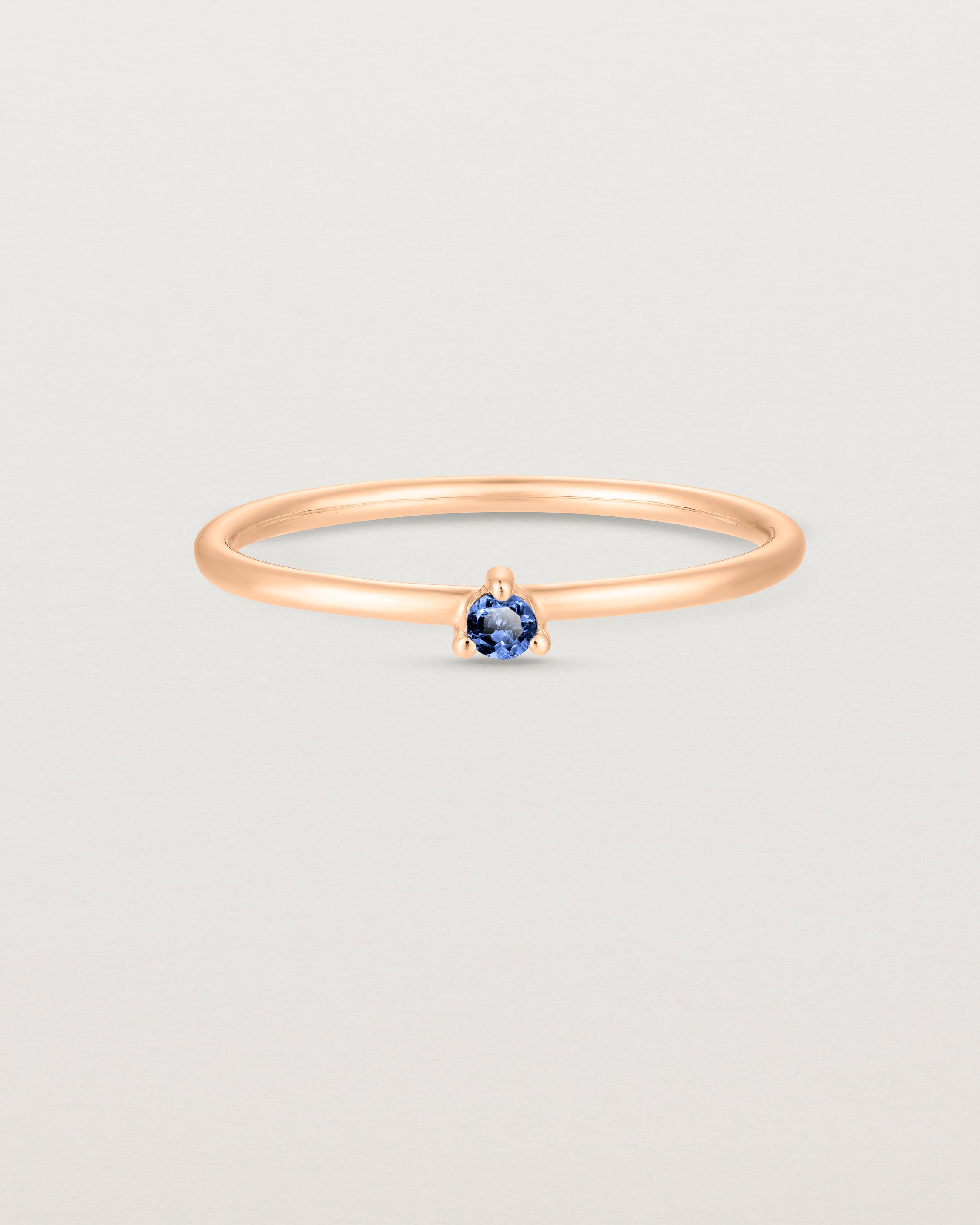 Front facing deep etched image of a rose gold ring with a blue sapphire birthstone.