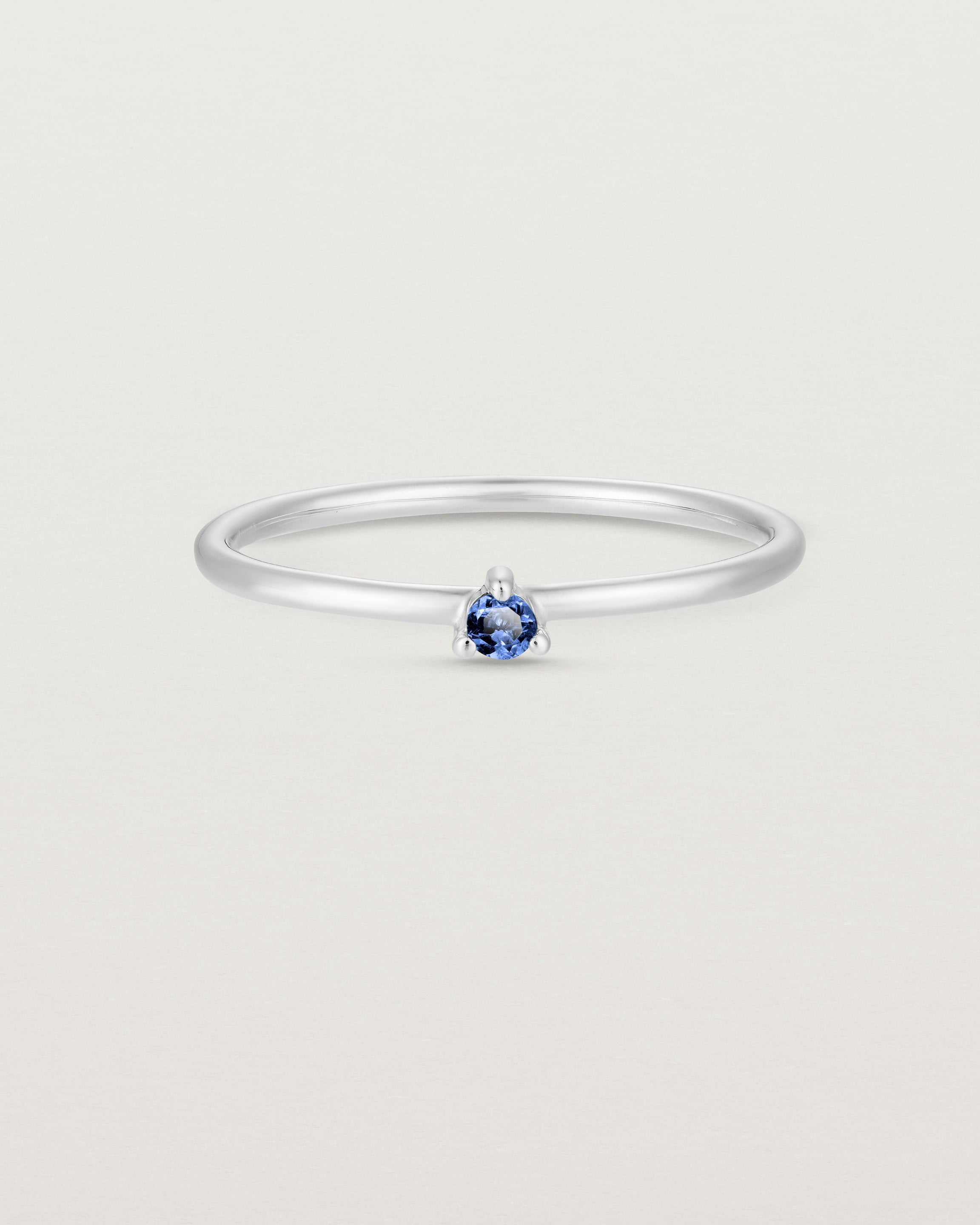 Front facing deep etched image of a white gold ring with a blue sapphire birthstone.