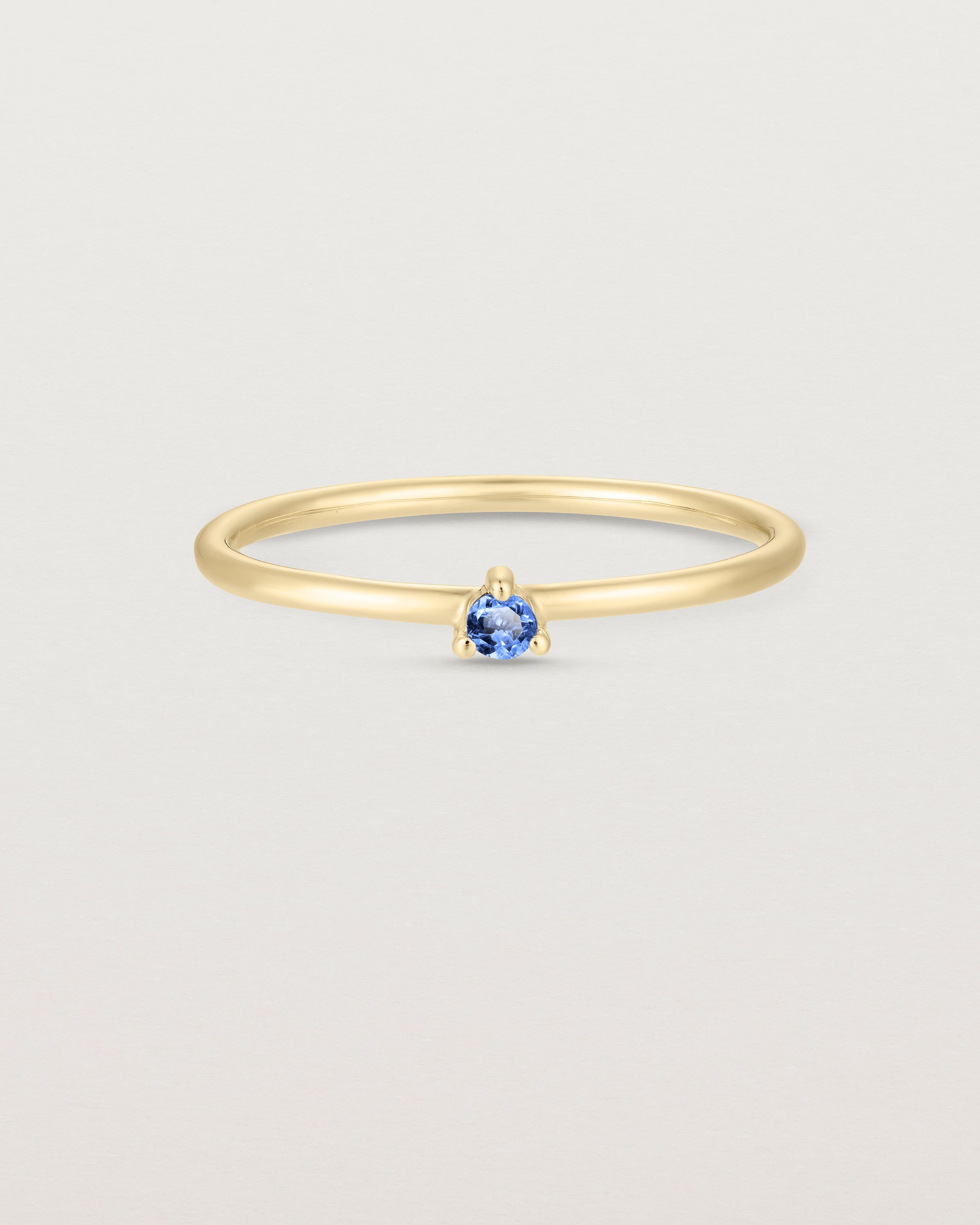 Front facing deep etched image of a yellow gold ring with a blue topaz birthstone.