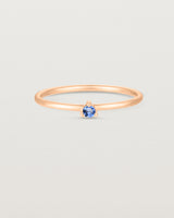 Front facing deep etched image of a rose gold ring with a blue topaz birthstone.