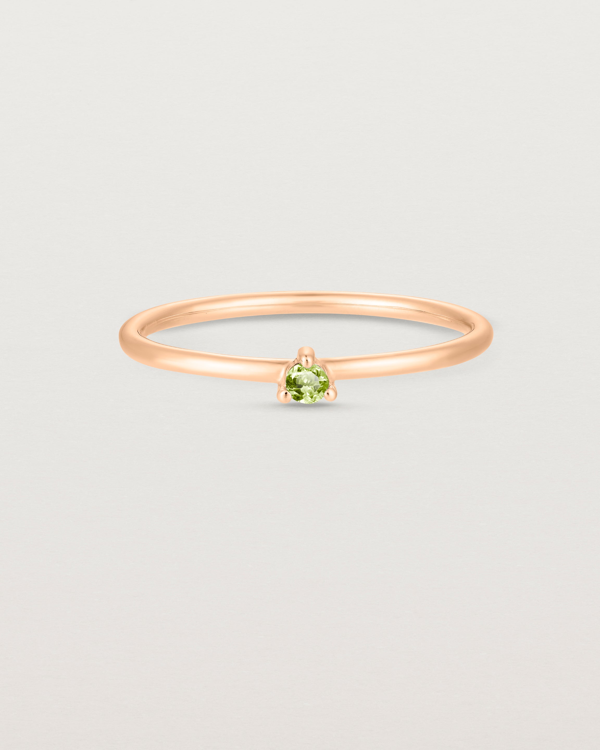 Front facing deep etched image of a rose gold ring with a peridot birthstone.