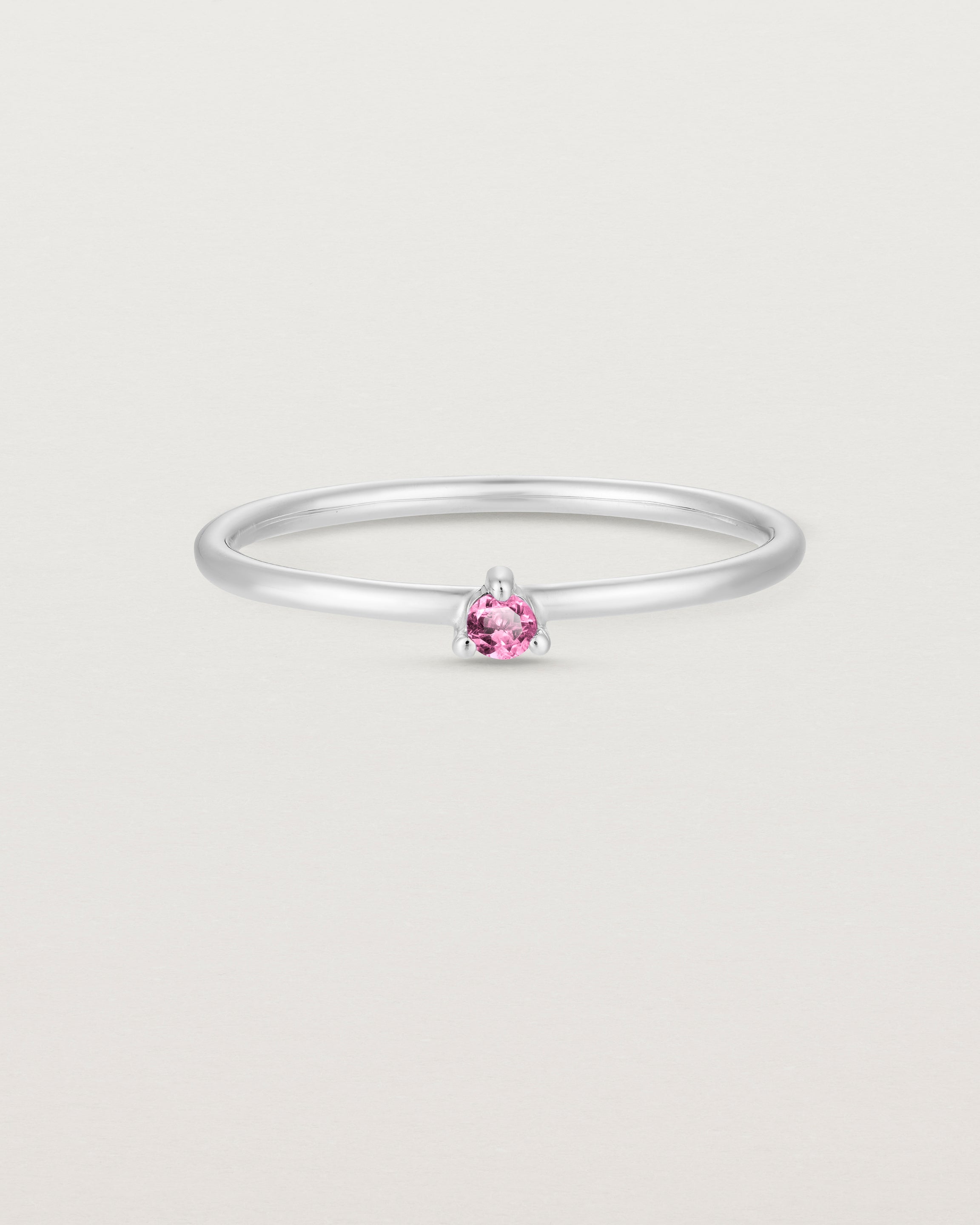 Front facing deep etched image of a white gold ring with a pink tourmaline birthstone.