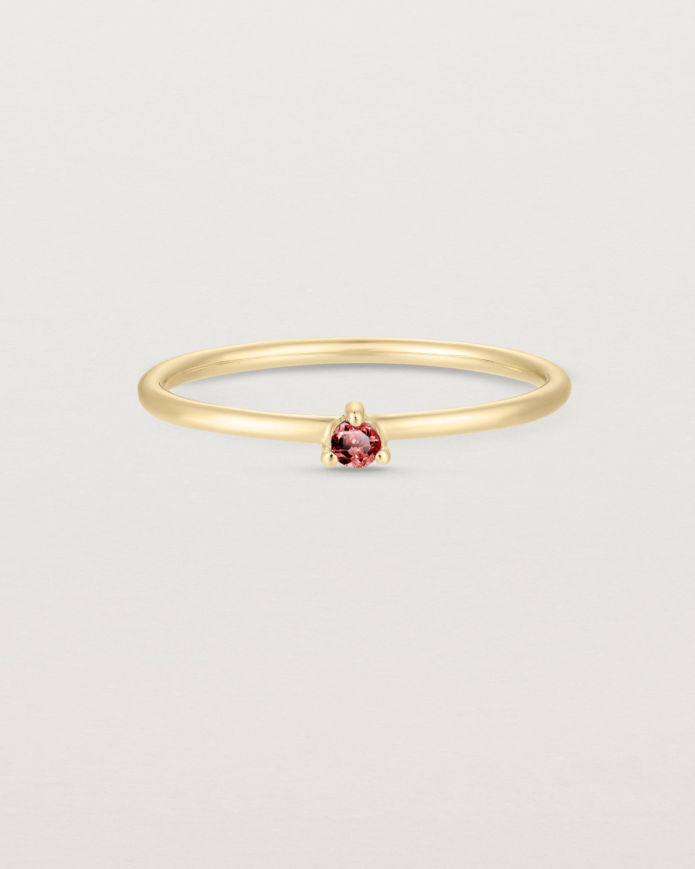 Front facing deep etched image of a yellow gold ring with a ruby birthstone.