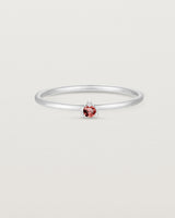 Front facing deep etched image of a white gold ring with a ruby birthstone.