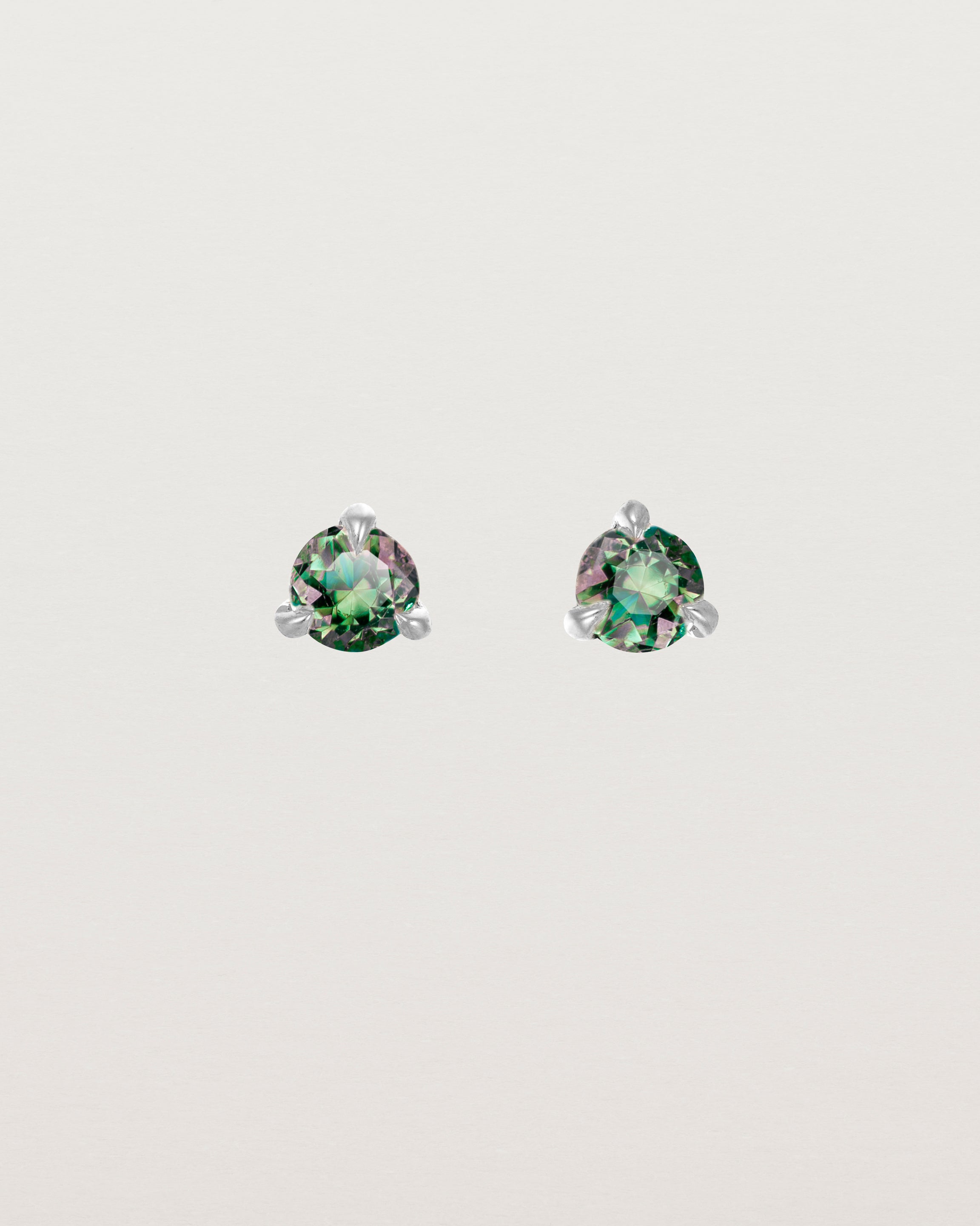 Front facing deep etched image of a pair of white gold earrings with an alexandrite birthstone.