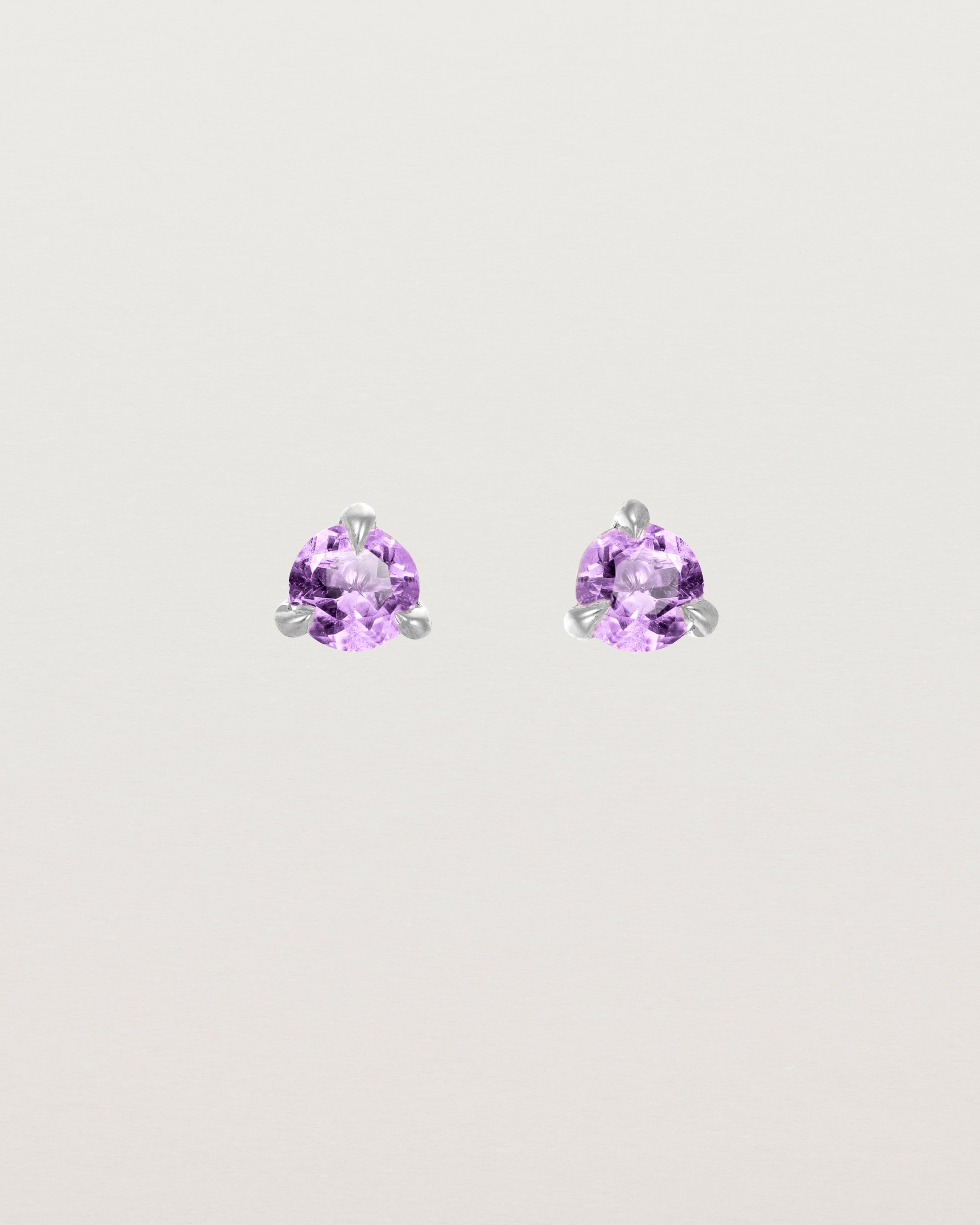 Front facing deep etched image of a pair of white gold earrings with an amethyst birthstone.