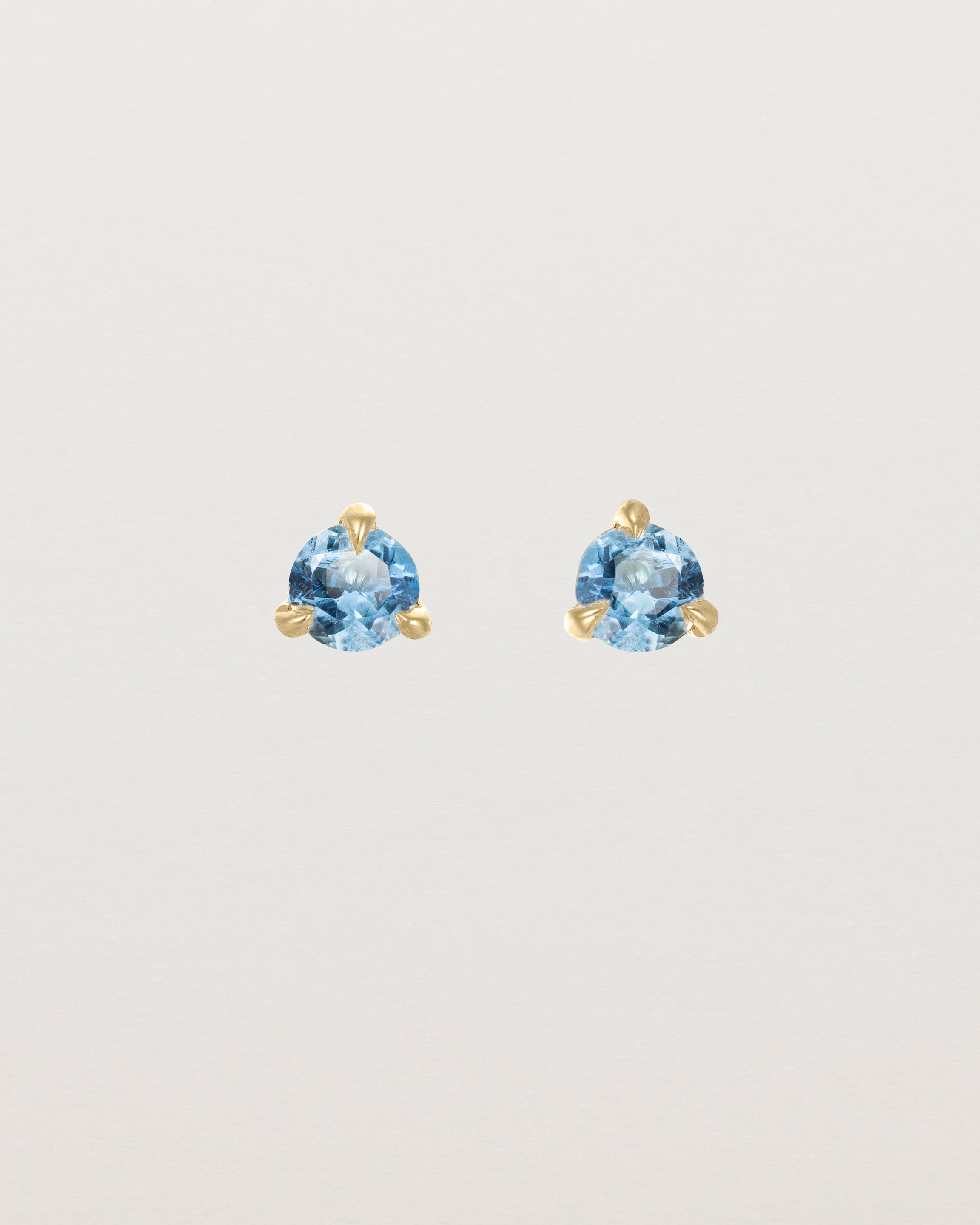 Front facing deep etched image of a pair of yellow gold earrings with an aquamarine birthstone.