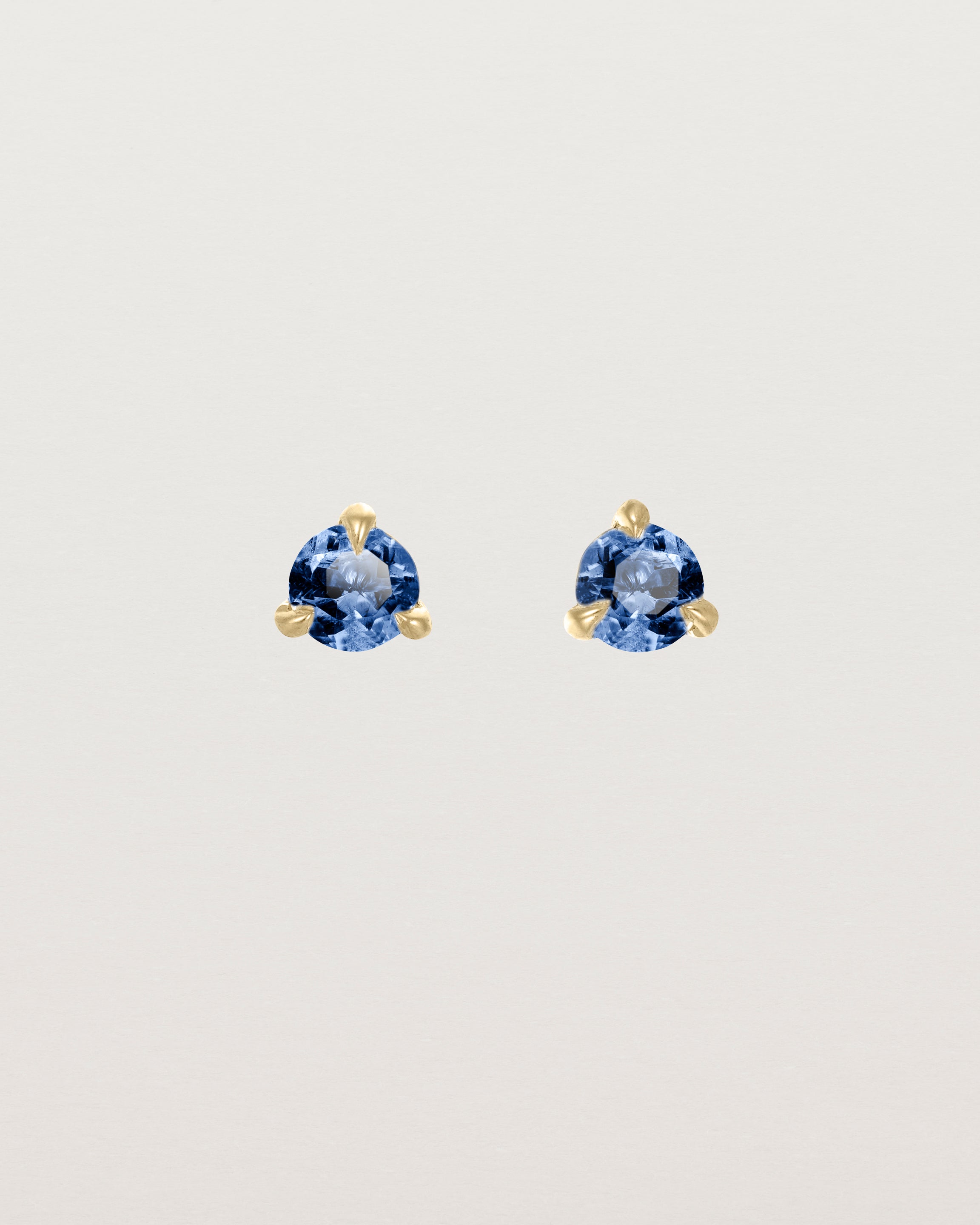 Front facing deep etched image of a pair of yellow gold earrings with a blue sapphire birthstone.