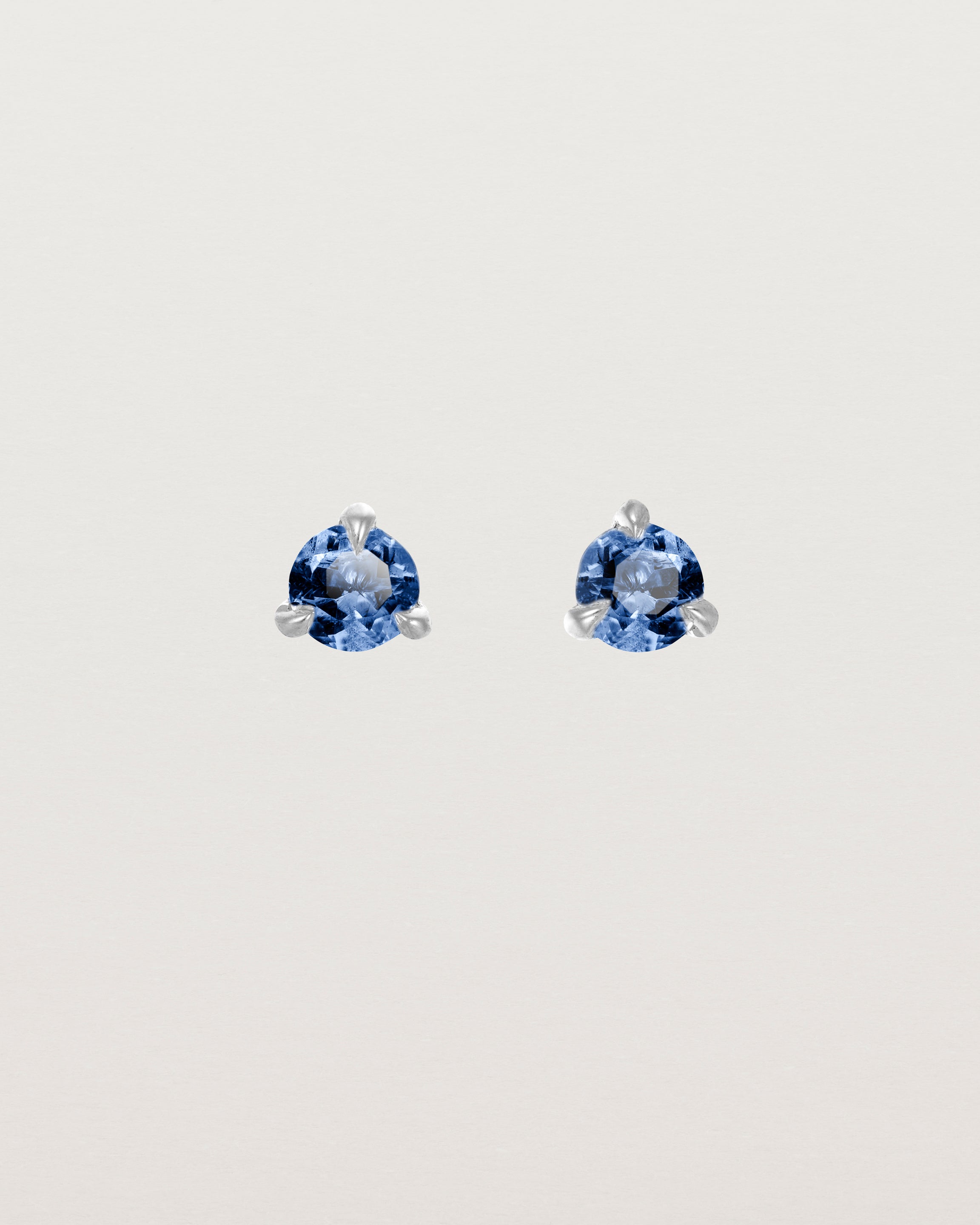 Front facing deep etched image of a pair of white gold earrings with a blue sapphire birthstone.