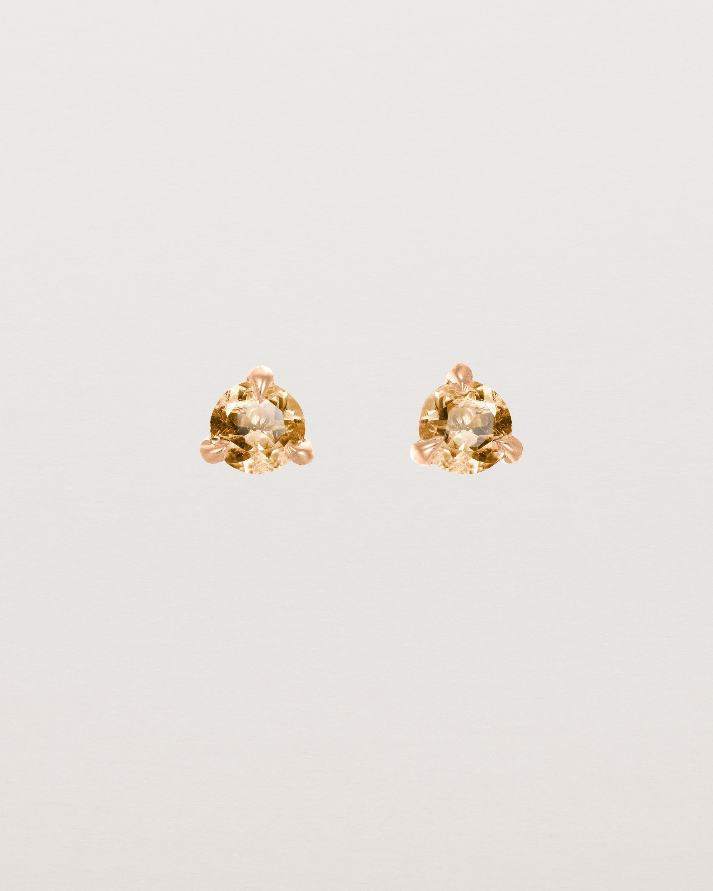 Front facing deep etched image of a pair of rose gold earrings with a citrine birthstone.