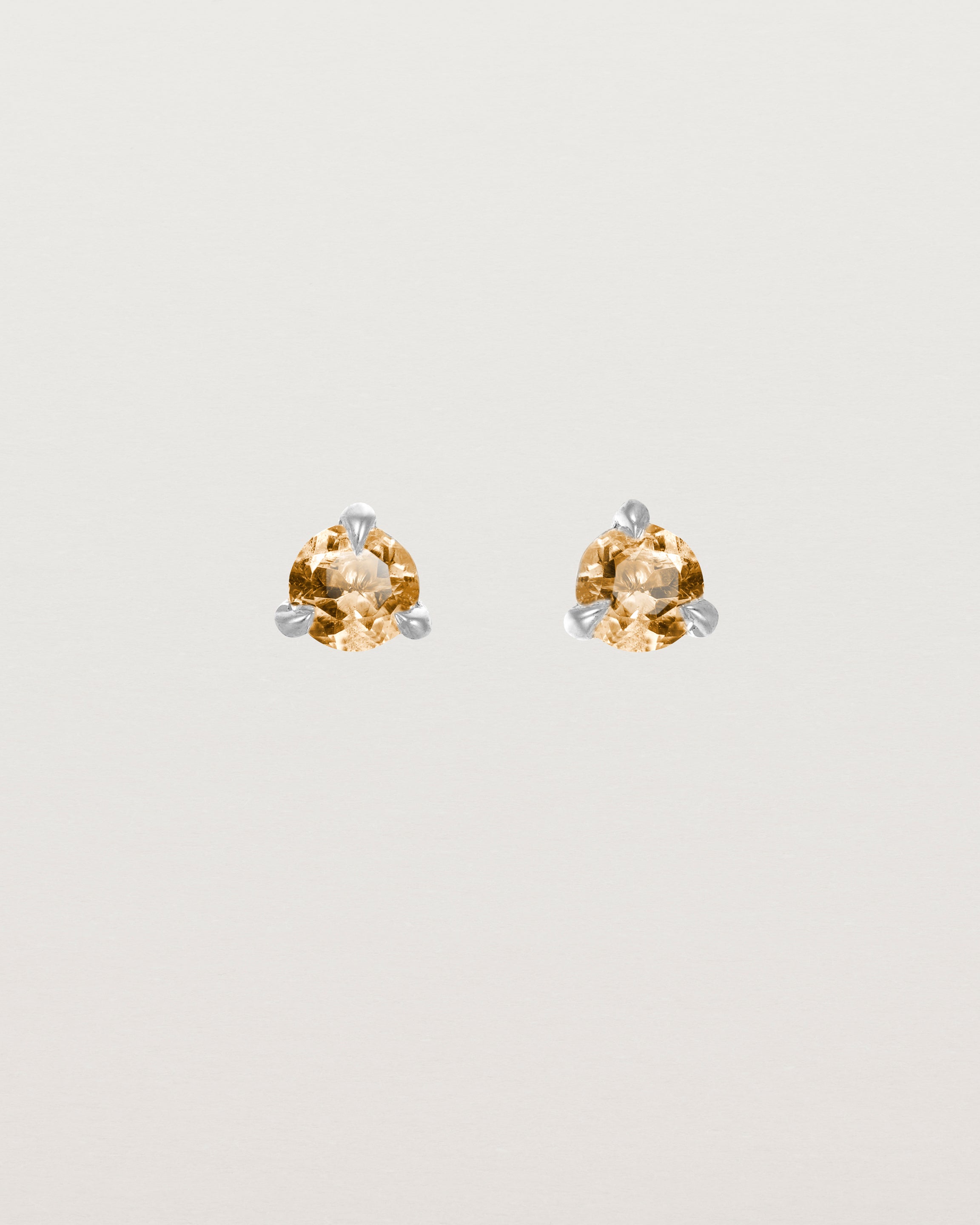 Front facing deep etched image of a pair of white gold earrings with a citrine birthstone.