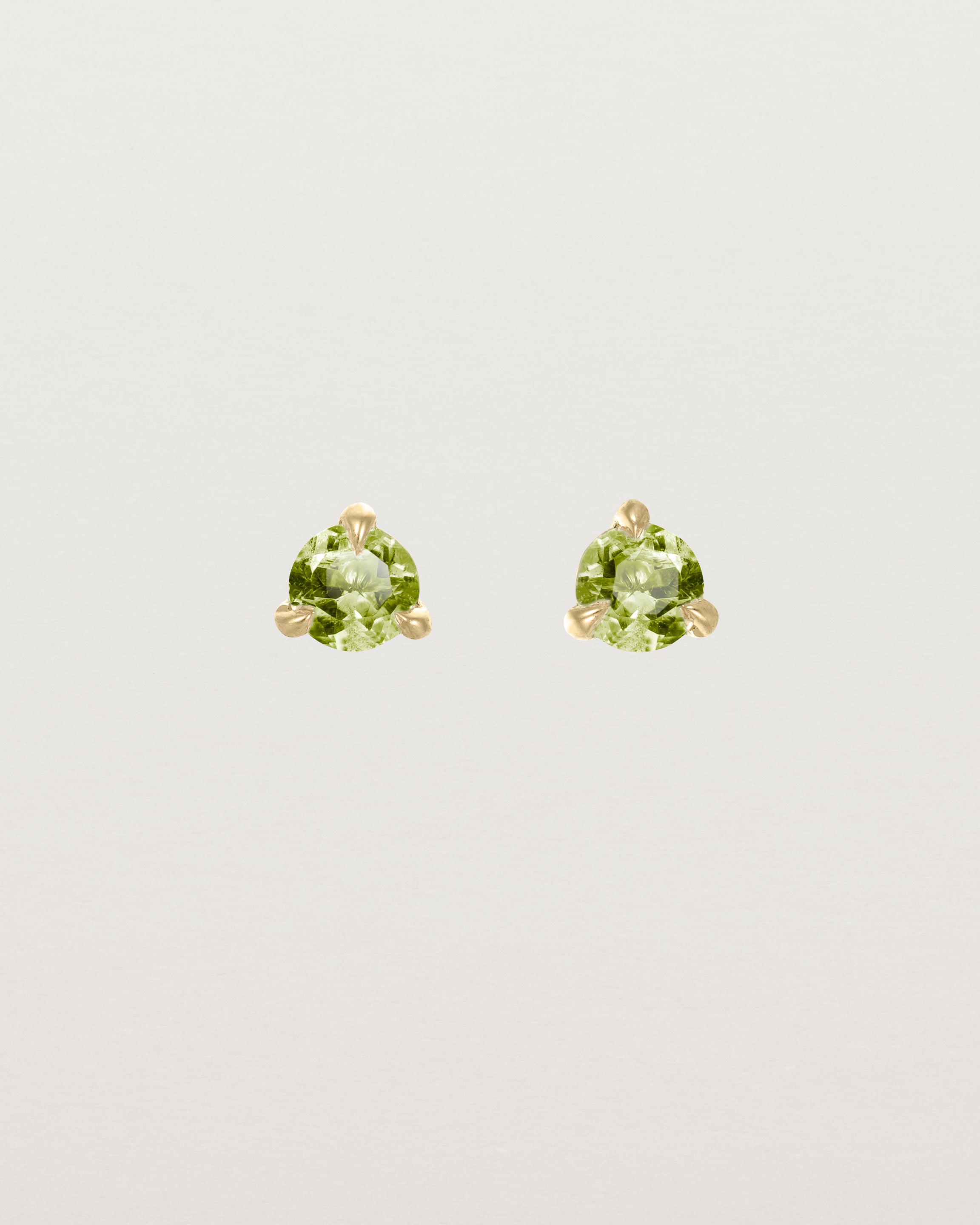 Front facing deep etched image of a pair of yellow gold earrings with a peridot birthstone.