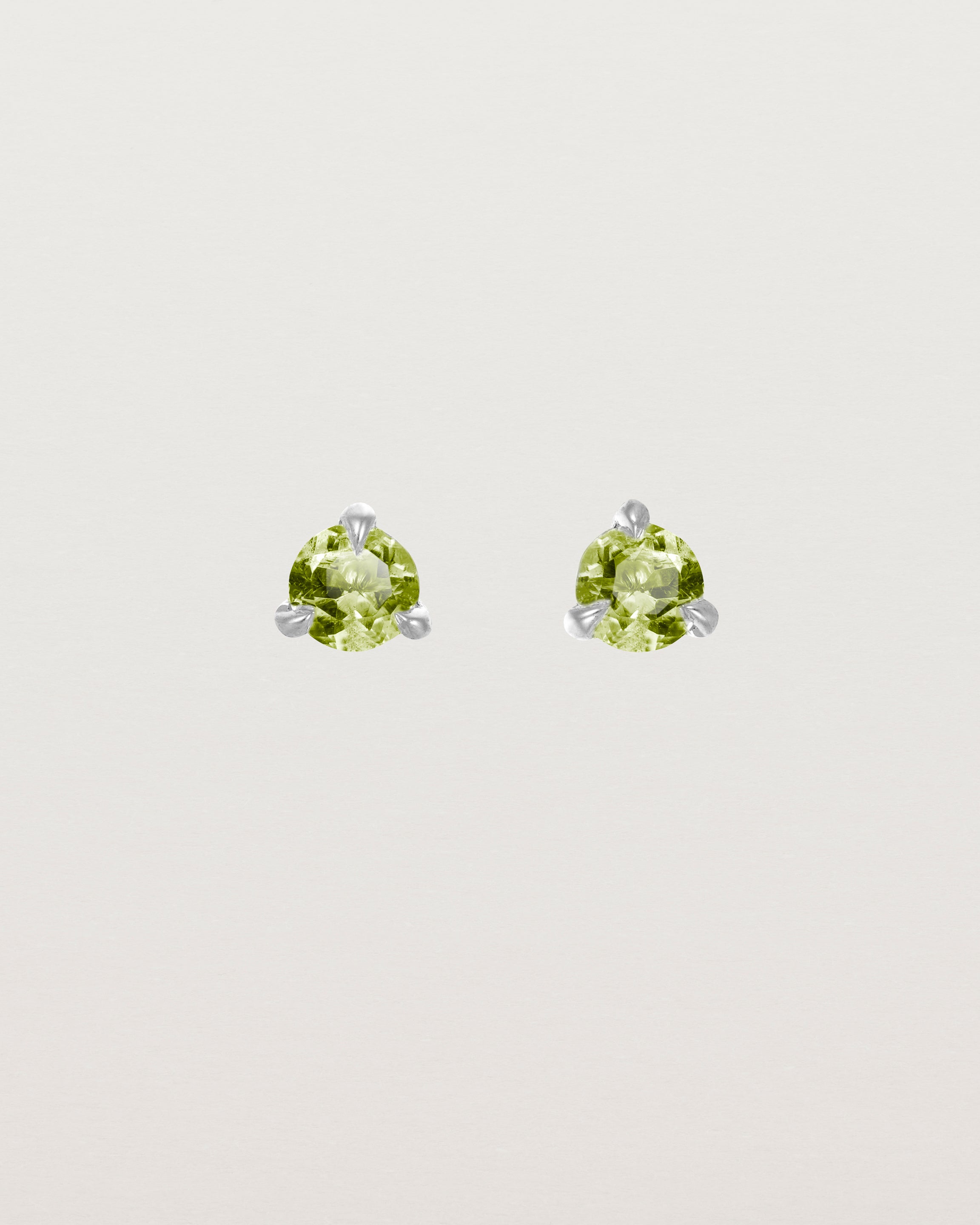 Front facing deep etched image of a pair of white gold earrings with a peridot birthstone.