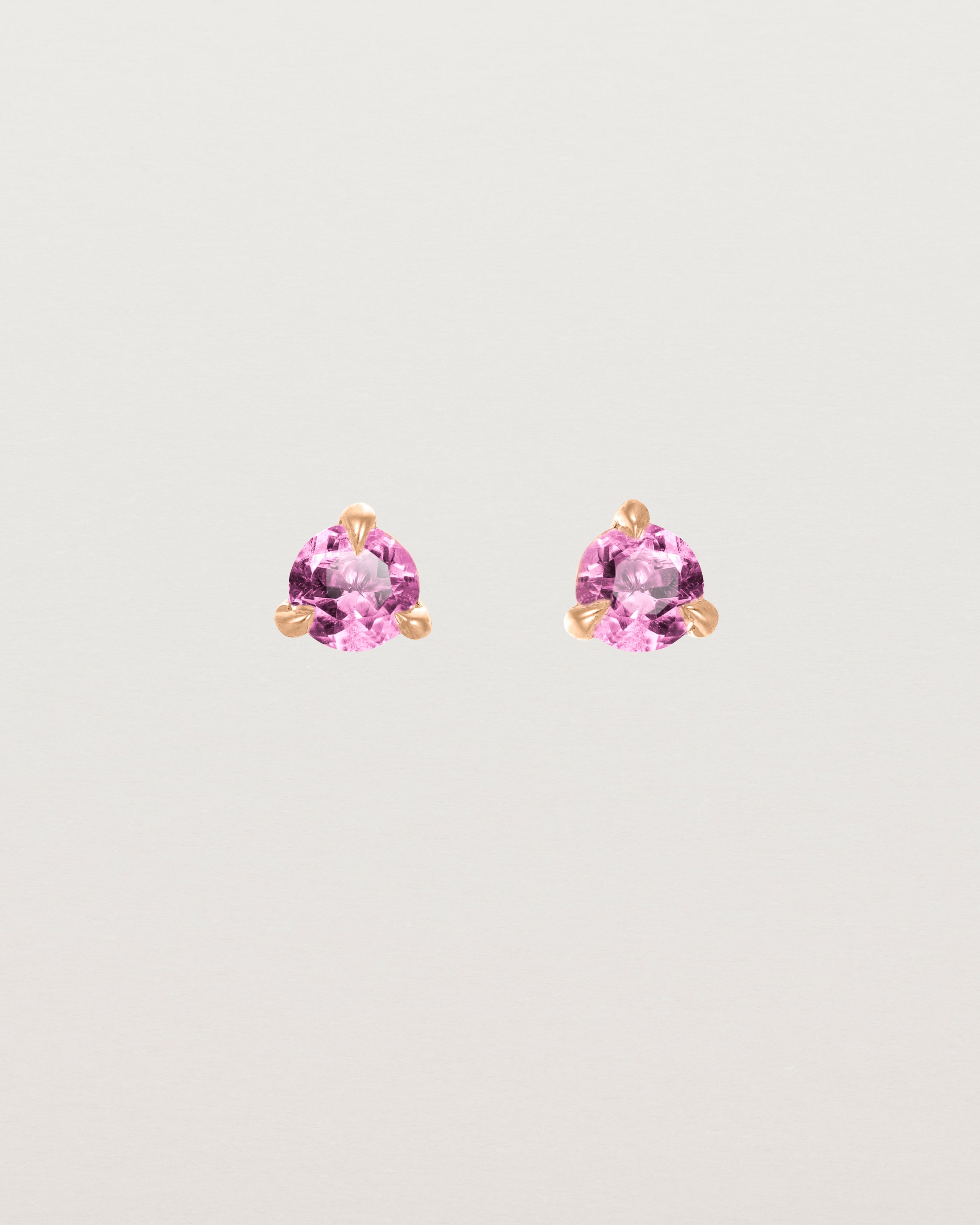 Front facing deep etched image of a pair of rose gold earrings with a pink tourmaline birthstone.