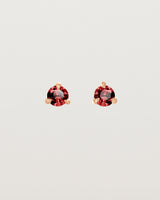 Front facing deep etched image of a pair of rose gold earrings with a ruby birthstone.