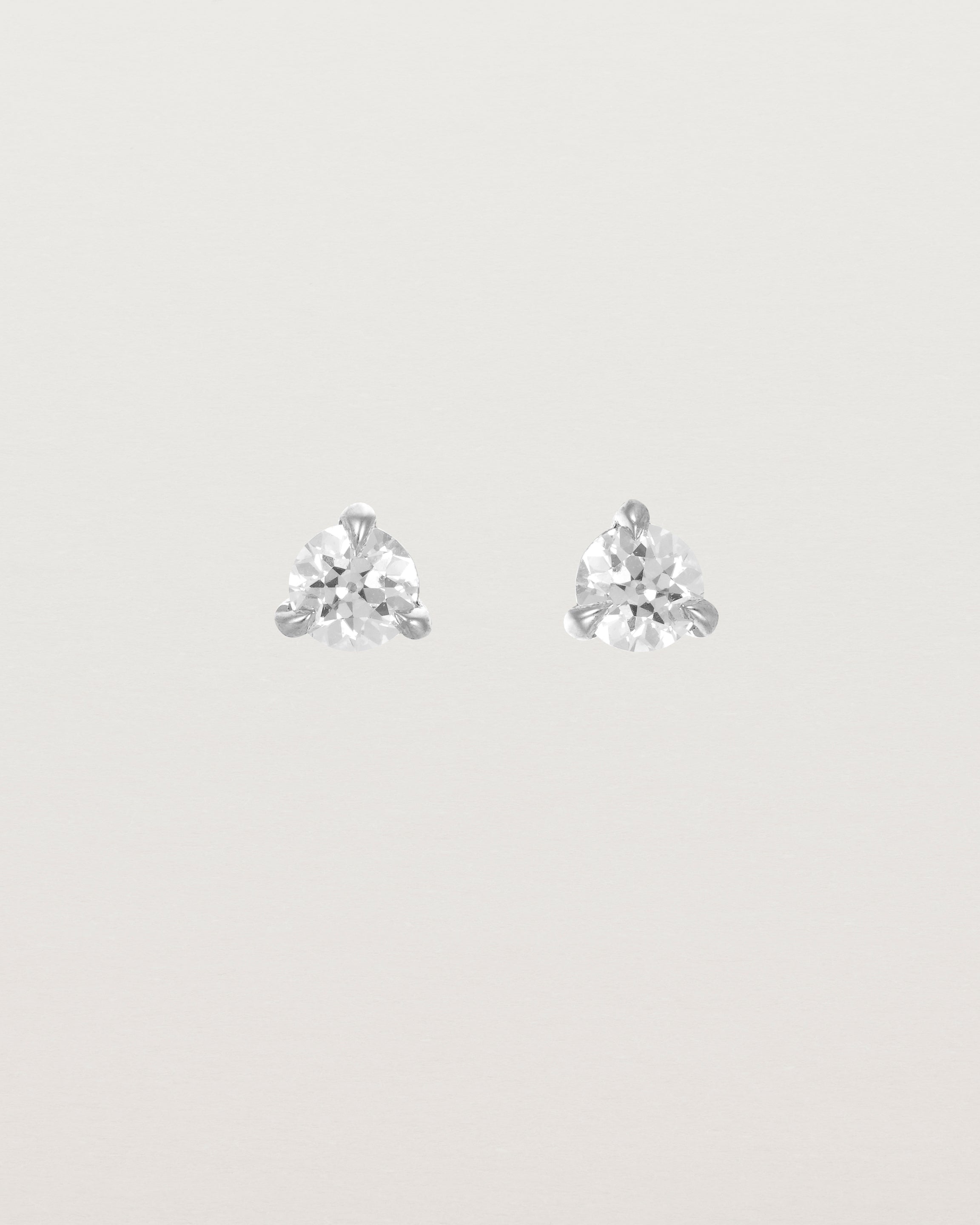 Front facing deep etched image of a pair of white gold earrings with a diamond birthstone.