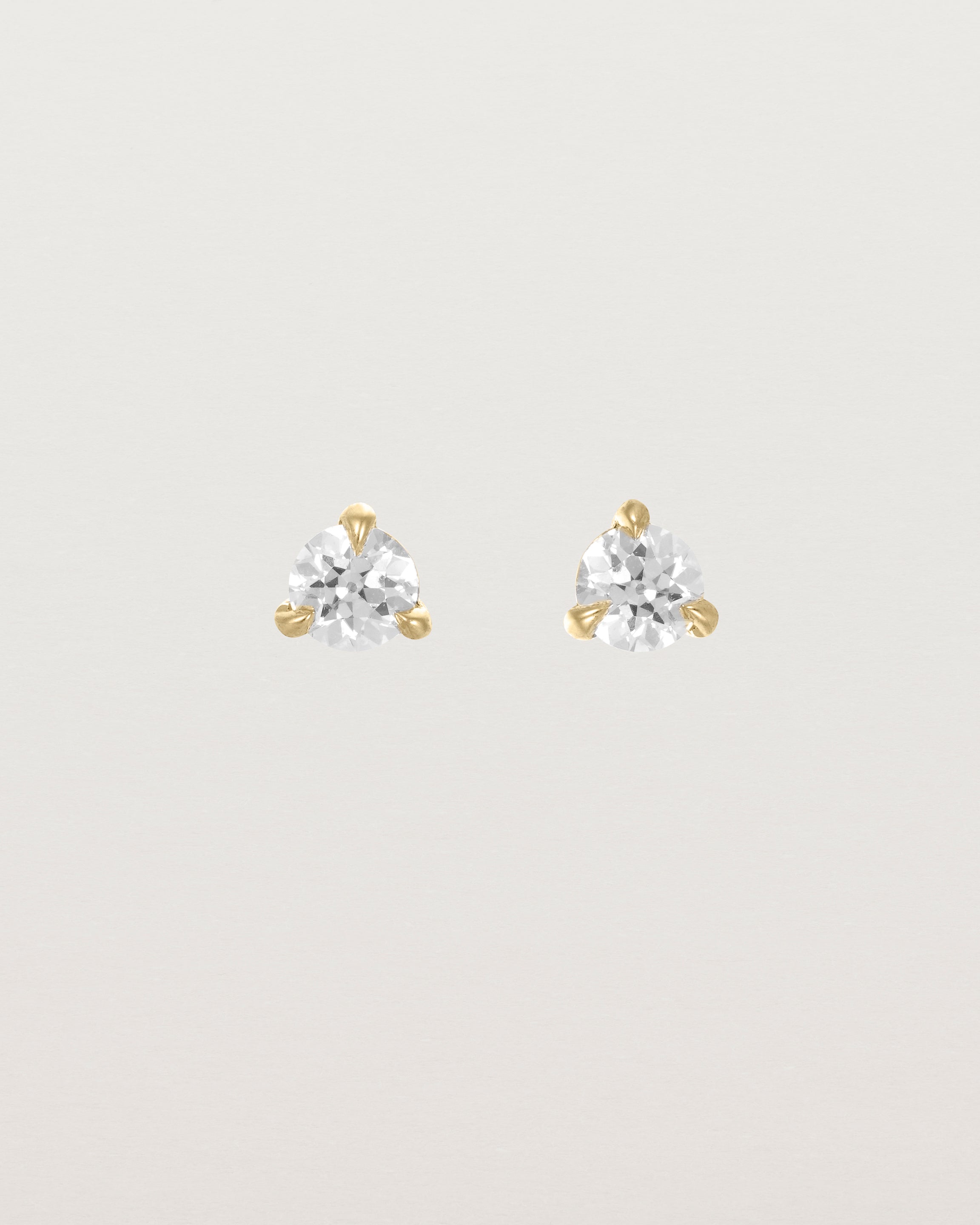 Front facing deep etched image of a pair of yellow gold earrings with a diamond birthstone.