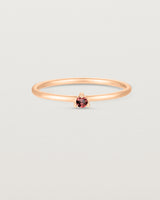 Front facing deep etched image of a rose gold ring with a garnet birthstone.