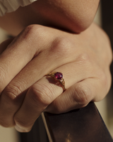 Close up image of woman wearing yellow gold vintage inspired ring with a cushion cut ruby.