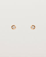 A small white circular rose gold stud featuring a white diamond