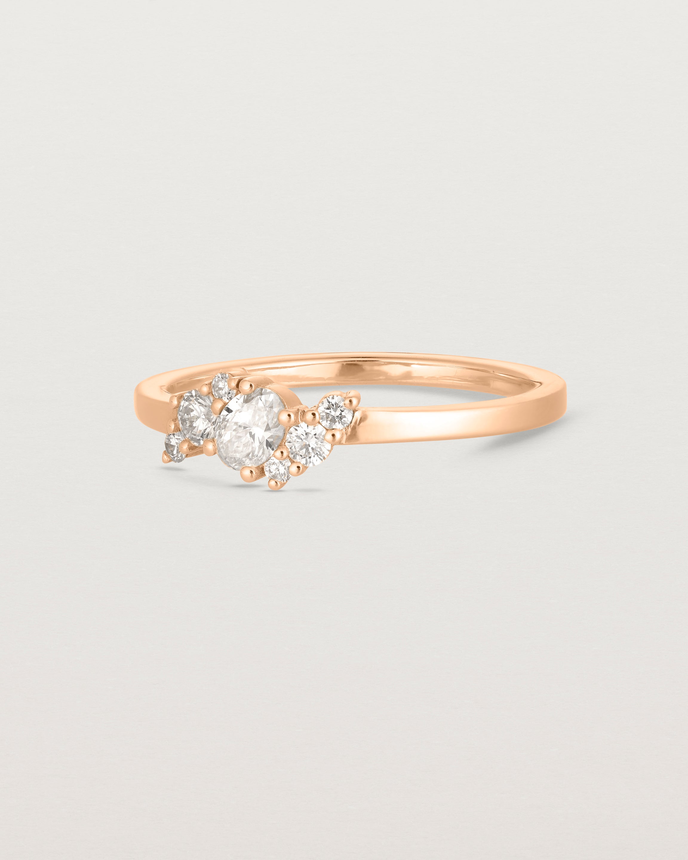 side on deep etched image of a rose gold  engagement ring with a cluster of 7 white diamonds