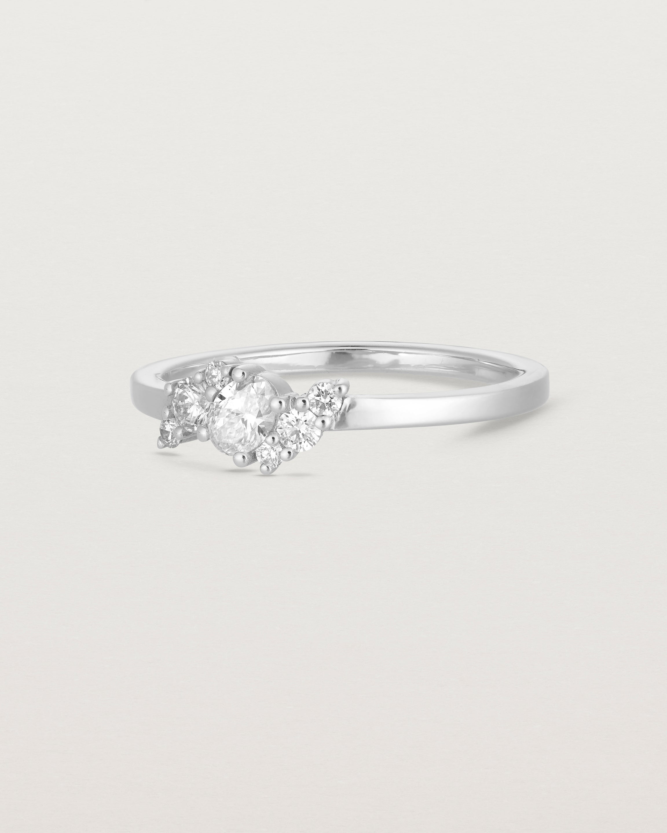 side facing deep etched image of a white gold  engagement ring with a cluster of 7 white diamonds