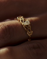 Close up image of a women wearing a vintage inspired yellow gold ring with an old mine cut pear diamond and intricate wire work.
