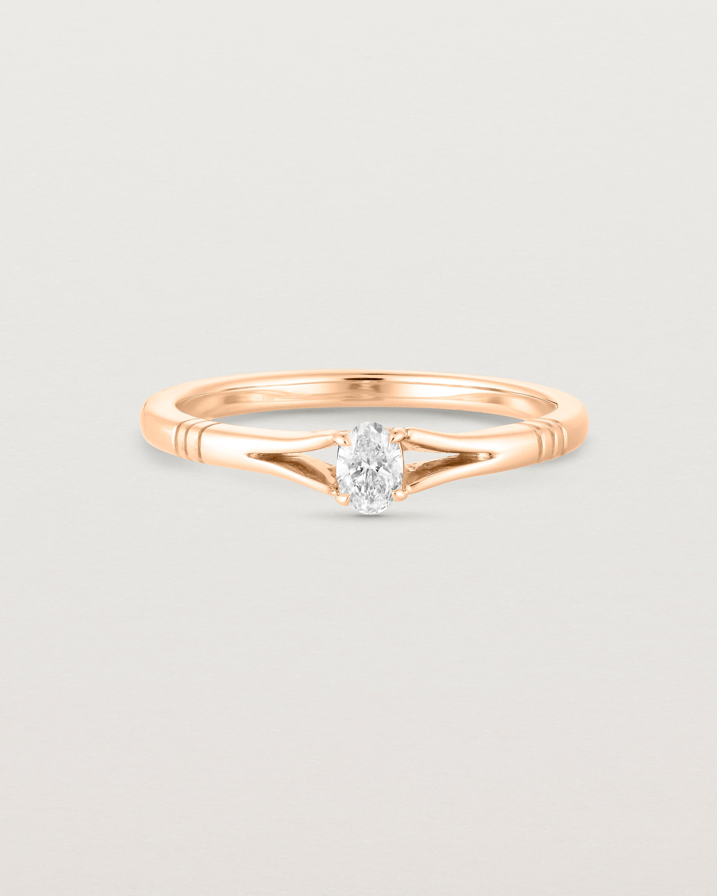 Front on deep etched image of a rose gold engagement ring with an oval diamond