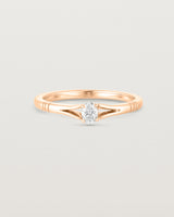 Front on deep etched image of a rose gold engagement ring with an oval diamond