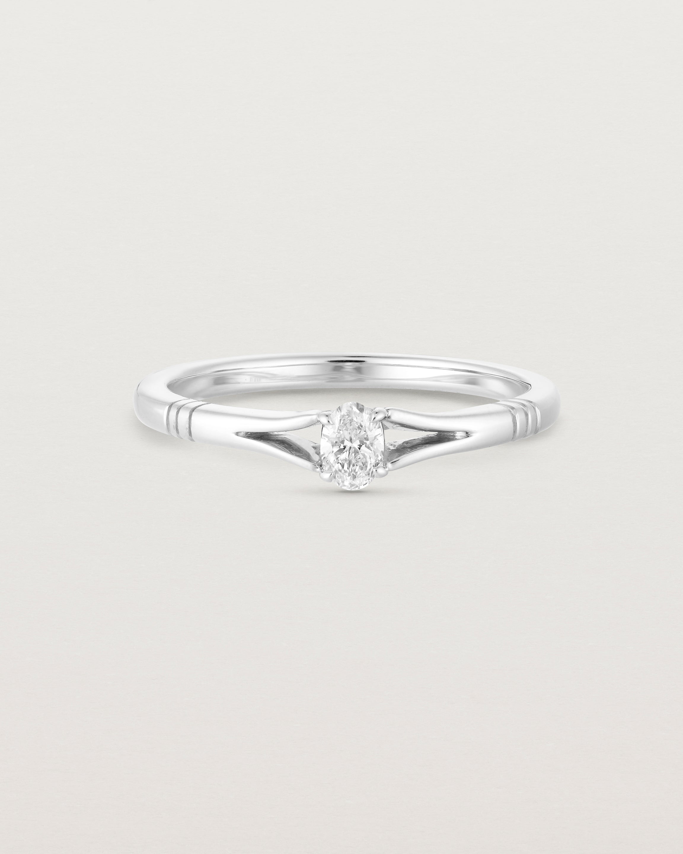 Front on deep etched image of a white gold engagement ring with an oval diamond.