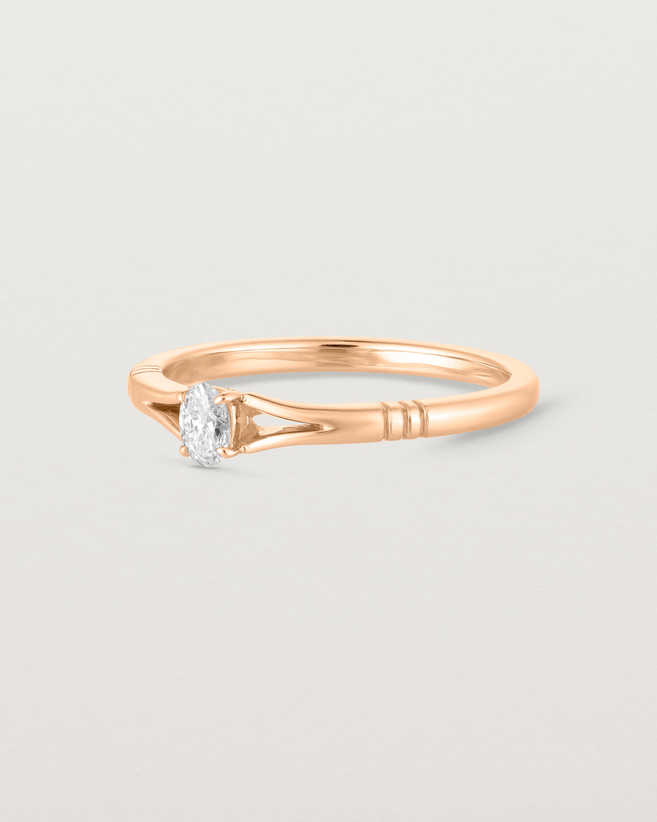 Side on deep etched image of a rose gold engagement ring with an oval diamond