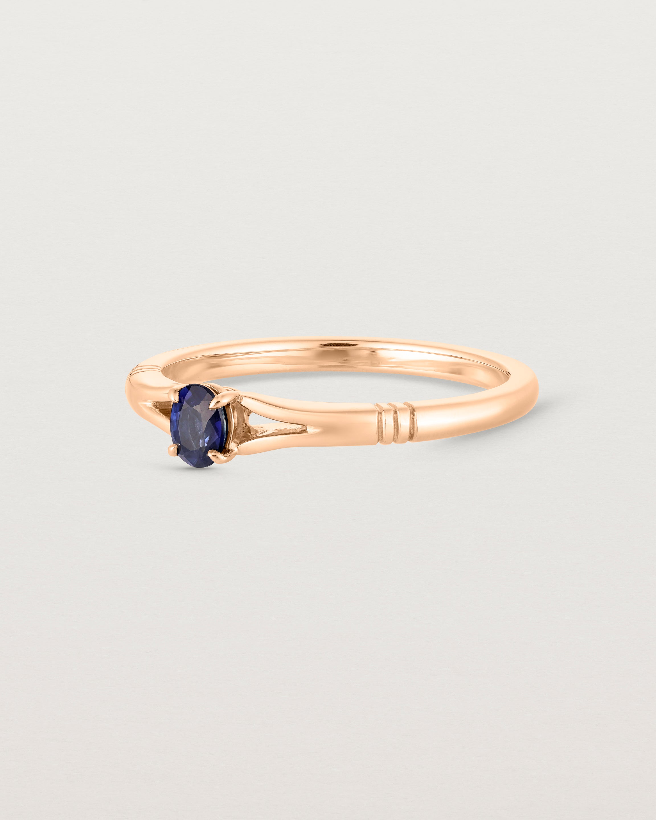 Side view deep etched image of a rose gold engagement ring with an oval sapphire stone