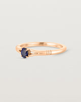 Side view deep etched image of a rose gold engagement ring with an oval sapphire stone