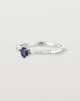 Side on deep etched image of a white gold engagement ring with an oval sapphire stone