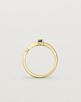 Standing deep etched image of a yellow gold engagement ring with an oval sapphire stone