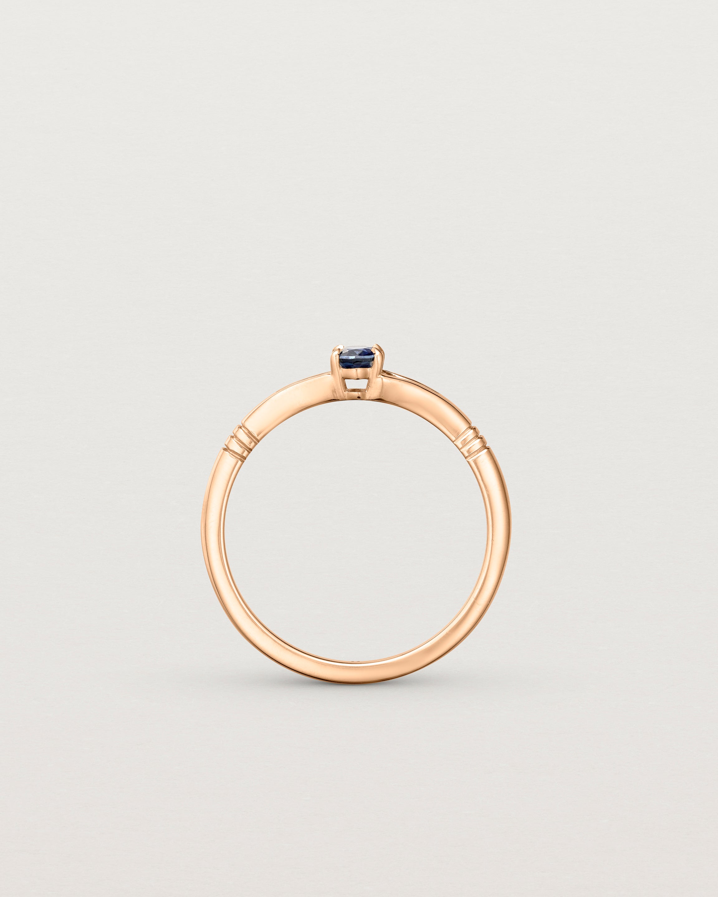 Standing deep etched image of a rose gold engagement ring with an oval sapphire stone